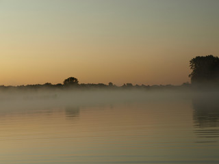 sunrise above a river on foggy summer morning, the sky reflections in the water,  misty reflection in steaming water, Salaca river, Latvia 