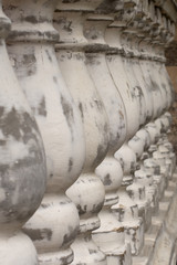 Antique balusters of gray color with cracked white paint. Linear perspective. Creative vintage background. Balustrade.