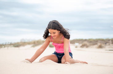 Pretty little girl playing with the sand on the beach