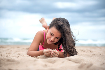 Pretty little girl playing with the sand on the beach