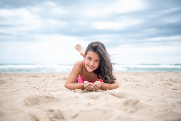 Fototapeta na wymiar Pretty little girl playing with the sand on the beach