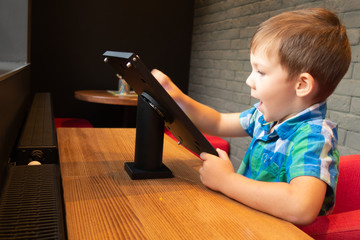 Children play on a tablet in a city cafe.