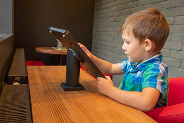 Children play on a tablet in a city cafe.