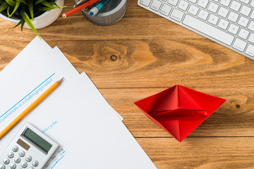 Wooden office desk with red origami boat