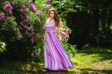 Obraz na płótnie Canvas Happy woman on a walk in spring park. Lilac trees on background.