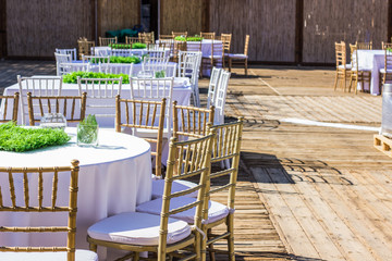 patio restaurant exterior decoration environment ready for some event wedding or birthday, wooden furniture chairs and table under white tablecloth