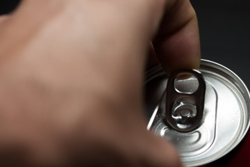 Fototapeta premium Hand opening a can of cold soda. Finger making strength to open the can. Cold drinks.