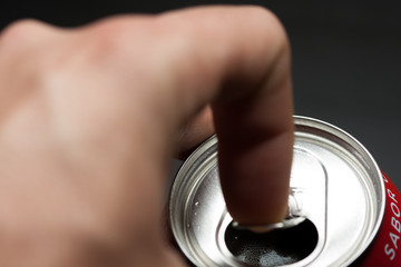 Hand opening a can of cold soda. Finger making strength to open the can. Cold drinks.