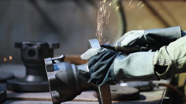 industrial safety first concept, Worker producing sparks from cutting a loop of steel pipe with a circular grinder