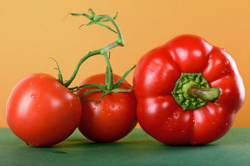 tomato and sweet pepper, paprika on the green table yellow background