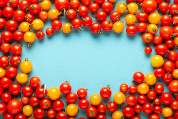 Red and yellow cherry tomatoes on blue background. Fresh bright organic vegetables.