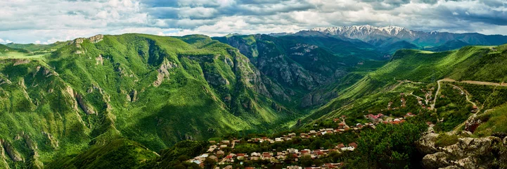 Fotobehang view of the village located in a mountain gorge on a bright sunny day with clouds in the sky. © StockAleksey