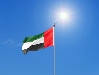 3D illustration. Colored waving flag of United Arab Emirates on sunny blue sky background.