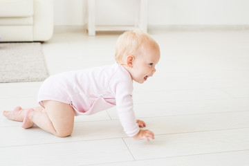 Childhood, children and babyhood concept - crawling funny baby girl indoors at home