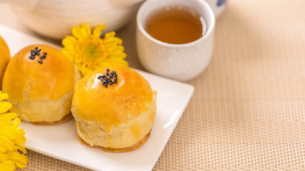 Tasty baked egg yolk pastry moon cake for Mid-Autumn Festival on bright wooden table background. Chinese festive food concept, close up, copy space.