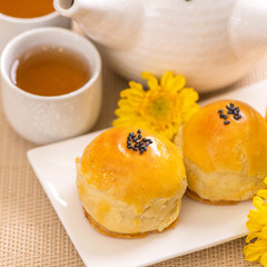 Tasty baked egg yolk pastry moon cake for Mid-Autumn Festival on bright wooden table background. Chinese festive food concept, close up, copy space.