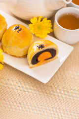 Tasty baked egg yolk pastry moon cake for Mid-Autumn Festival on bright wooden table background. Chinese festive food concept, close up, copy space.
