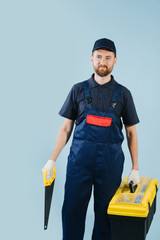 Portrait of confident service worker with saw and tool case, dressed in uniform