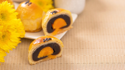 Tasty baked egg yolk pastry moon cake for Mid-Autumn Festival on bright wooden table background. Chinese festive food concept, close up, copy space.
