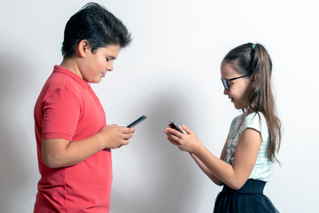 A little girl and a boy looking at smartphones. Children are passionate about social networks