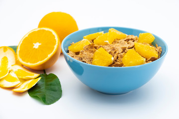 Cereal flake with pieces orange fruits slice in the blue bowl isolated on white background