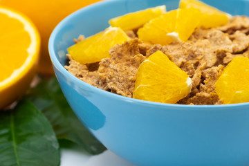 Cereal flake with pieces orange fruits slice in the blue bowl isolated on white background