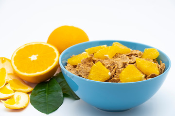 Cereal flake with pieces orange fruits slice in the blue bowl isolated on white background