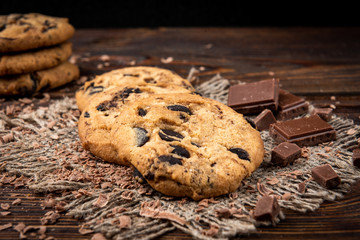 Cookies with chocolate on dark wooden background.