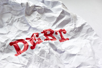 Wrinkled white paper with the word debt printed in red. Concept of debt free life or financial freedom.
