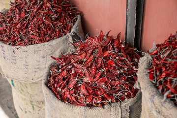 Dried red chilly kept in a gunny sack outside a shop in a spice market. background - image