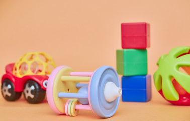 top view of children's educational toys. Bright plastic, a plastic set of toys for children. Flatlay with space for text on a peach background.