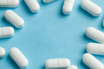 White pills on blue background. One tablet is broken in half, reducing the dose of the medicine