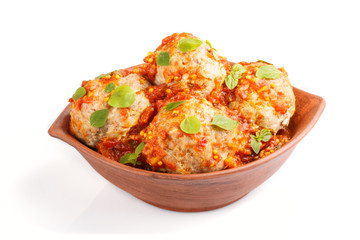Pork meatballs with tomato sauce, oregano leaves, spices and herbs in clay bowl isolated on white background. side view
