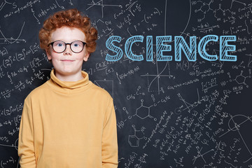 Smart little boy with red ginger hair on science background