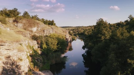 Aerial shot with drone flying close to the water in canyon during sunny day
