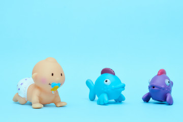 Vintage crawling doll for swimming with colored fish on a blue background, a rubber doll of a little boy. Copy space isolator. children's toys for children.