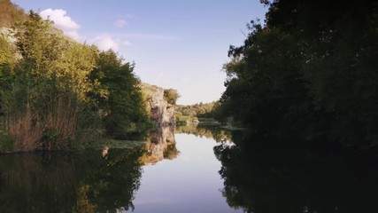 Aerial shot with drone flying close to the water in canyon during sunny day