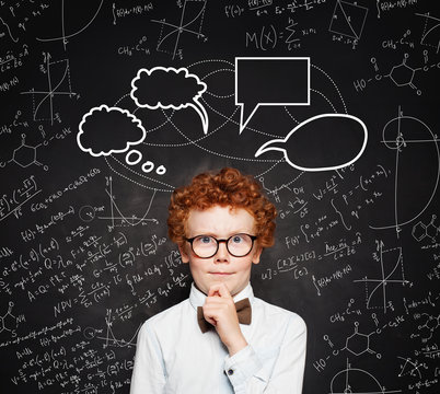 Little smart boy in white shirt and bow tie on chalkboard background with empty speech clouds bubbles