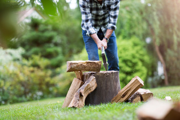 Senior man cutting logs, working in the garden