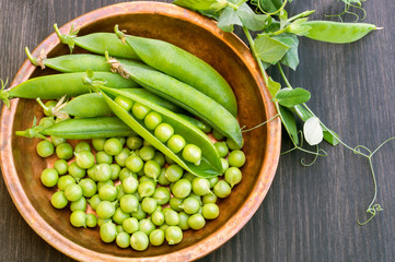 Young green peas on white wooden background.