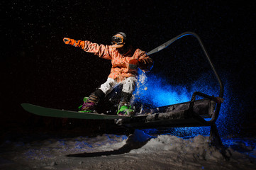Male snowboarder dressed in a orange sportswear jumping from the funicular