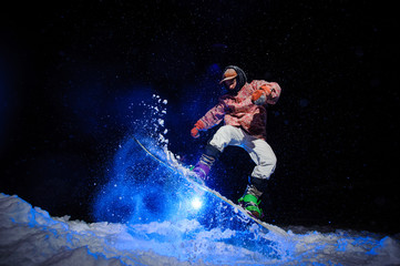 Male snowboarder dressed in a white and pink sportswear performs tricks on the snow slope
