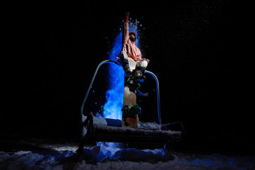 Male snowboarder dressed in a white and pink sportswear sitting on the funicular seat