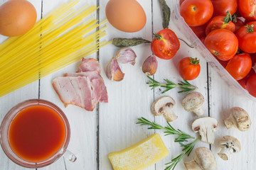 Frame with spaghetti and various ingredients for cooking pasta on a white background