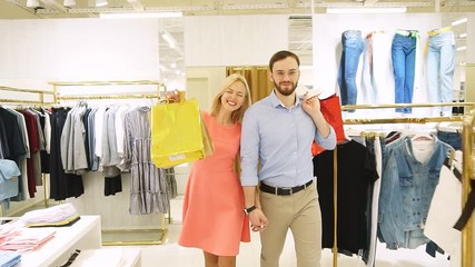 young happy couple shopping together clothes at fashion shop. Slow motion