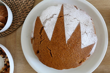 Homemade sponge cake served on a table with dishware, cookies, nuts and vase of flowers. Top view.