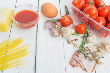 Frame with spaghetti and various ingredients for cooking pasta on a white background