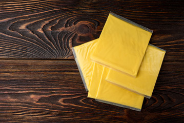 Processed cheese on dark wooden background.
