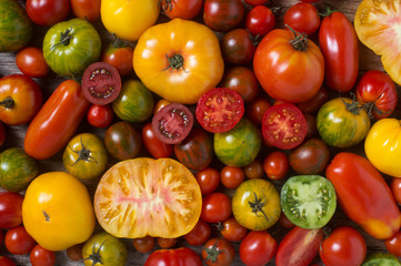Close up of colorful tomatoes, some sliced, shot from above - obrazy, fototapety, plakaty
