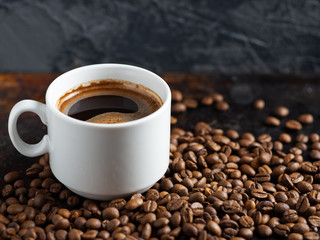 White Cup of espresso close-up on roasted coffee beans